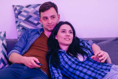 Kanepede bir çift. Adamın elinde uzaktan kumanda var..