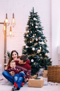 Noel ağacının yanında oturan aynı elbiseli bir aile. şık iç tasarım.