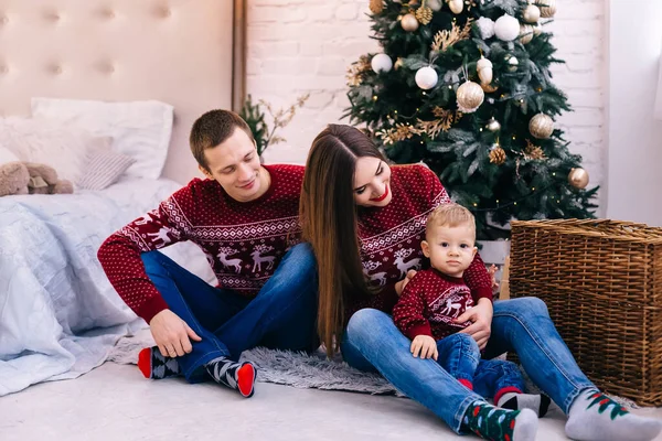 両親と小さな男の子がクリスマスツリーとベッドの近くに座ってる 家族みたいに — ストック写真