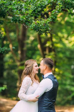 Ağaçların arka planında yeni evlilerin kollarındaki profilleri..