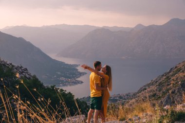 Man and woman couple tourists enjoying the view of Kotor. Montenegro. Bay of Kotor, Gulf of Kotor, Boka Kotorska and walled old city.