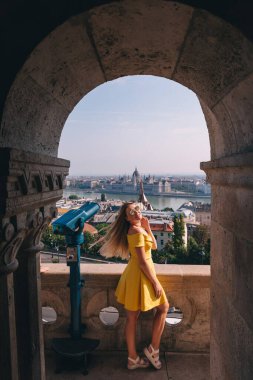 Avrupa 'da turizm. Budapeşte 'deki Tuna Nehri' ndeki Macar Parlamentosu binasının manzarasının keyfini çıkaran, elbise giymiş genç bir kadının resmi..