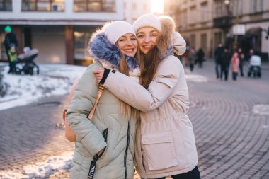 İki mutlu kız arkadaş uzun bir ayrılıktan sonra şehrin sokaklarında birbirlerine sarılıyorlar.