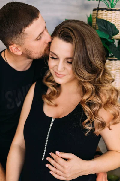 幸せな男が抱きかかえて居心地の良いアパートで妊娠中の妻とキスをして — ストック写真
