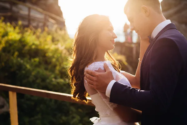 新娘温柔地爱抚着丈夫 用充满爱心的眼睛望着他 在夕阳西下的背景下拥抱他 结婚的概念 — 图库照片