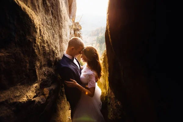 一对浪漫的夫妇在遥远的山中的某个地方 在日落的背景下拥抱地站在岩石之间 — 图库照片