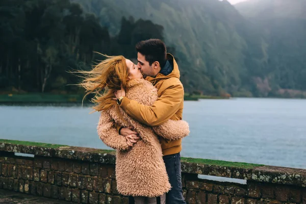 男は女の子にキスし 湖や山の近くで抱きしめます クローズアップ — ストック写真