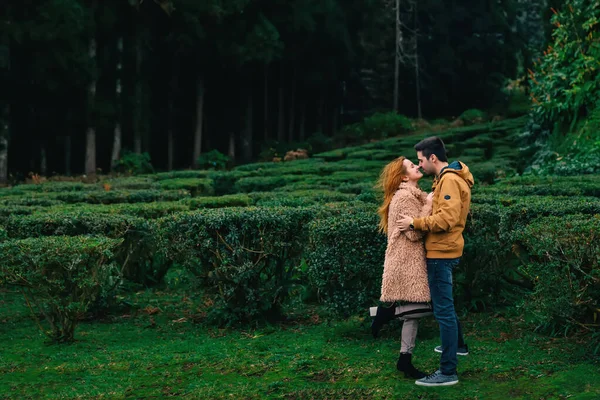 女の子が足を上げて男が抱きかかえてキスしたがってる 公園だ プロフィール — ストック写真