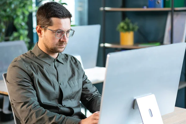 Vážné Pohledný Vousatý Muž Ležérní Košili Sedí Pracovišti Pracuje Počítačem — Stock fotografie