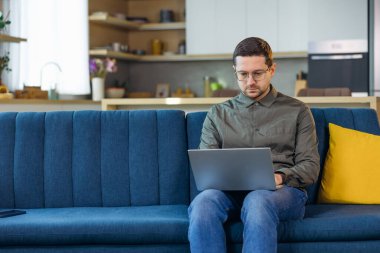 Uzak İş. Evde Kanepede Oturan Laptop Üzerinde Çalışan Adam. Metin için Boş Alan