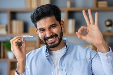 Diş düzeltmesi yapan yakışıklı bir genç. Parmaklarıyla imza atıyor. Mükemmel bir sembol.