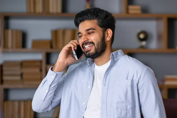 Happy smiling indian professional business man talking on cell phone, eastern businessman making mobile phone call by cellphone in office.