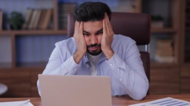 Genç Hintli İspanyol adam masada dizüstü bilgisayarla çalışıyor.