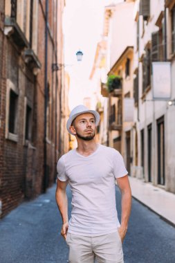 Beyaz giysiler ve hasır şapka şehir sokakta sakallı bir adam. adam elini hasır şapka üzerinde tutar.