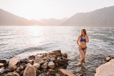 Mutlu sarışın kadın Adriyatik Denizi 'ndeki adalarda yüzünü güneşe koyar. Karadağ 'da tatilde olan kız.