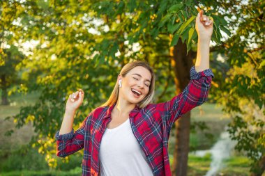 Yeşil arka planda izole edilmiş günlük giysiler içinde neşeli, mutlu bir genç. İnsanların yaşam tarzı konsepti. Kopyalama alanı oluşturun. Kulaklıkla müzik dinlemek, şarkı söylemek, dans etmek.