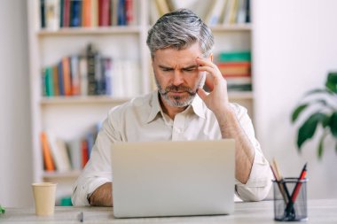 Sorunları düşünüyorum. Yorgun kıdemli işadamı elini şakağına koyar problem çözmeyi düşünür, uzaktan çalışır.