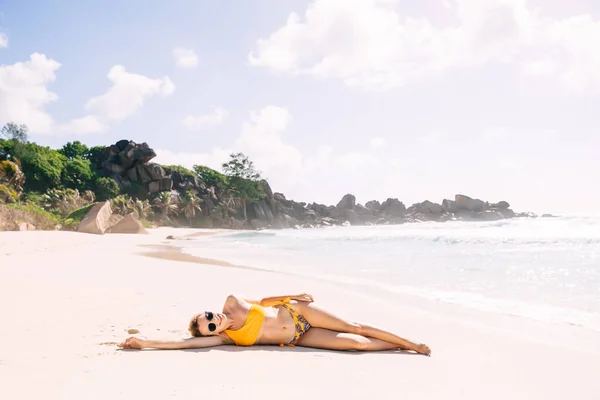 美丽的女人 身材匀称 躺在沙滩上 身穿橙色泳衣 在海滨度假胜地日光浴 享受暑假 — 图库照片