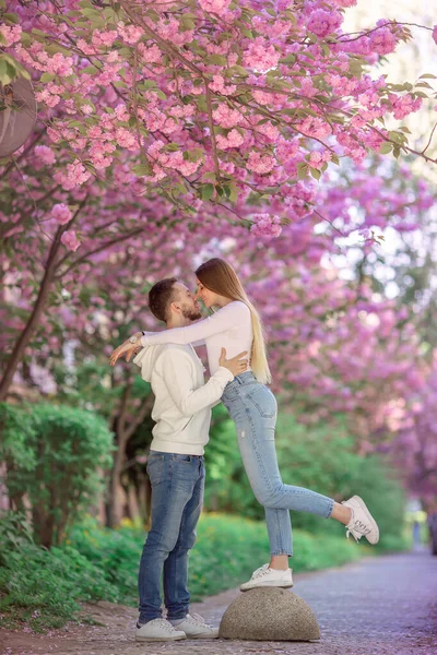 街の通りに桜の木が咲く近くに幸せなスタイリッシュなカップル 春の家族の表情 — ストック写真