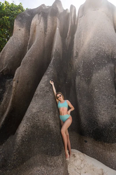 熱帯の島の岩場に佇むビキニ姿の信じられないほど魅惑的なビーチガールモデル ブロンドファッション女性とともに完璧なボディ 夏休みを楽しんでポーズ — ストック写真