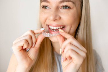 Young woman holding invisible aligner. Dental health, beautiful smile clipart