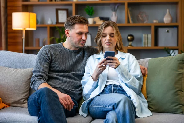 Joyeux Jeune Couple Assis Sur Canapé Maison Utilisant Téléphone Mobile — Photo