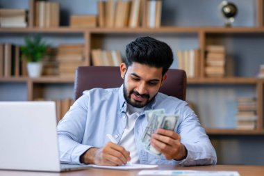 İş, finans, muhasebe ve insan konsepti. Ofiste parası ve hesap makinesi olan adam kağıtları dolduruyor.