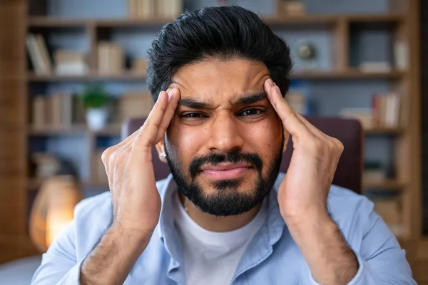 慢性片頭痛に苦しむ頭痛を感じる不健康な疲れたアラブ人慢性片頭痛に苦しむビジネスマンは オフィスの仕事の後に疲労を感じるノートパソコンで痛みに苦しむ頭に触れる痛みに苦しむ — ストック写真
