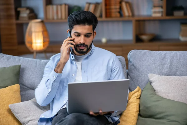 Neşeli Hintli Adam Evde Çalışırken Bilgisayarını Kullanarak Telefonla Konuşuyor Genç — Stok fotoğraf