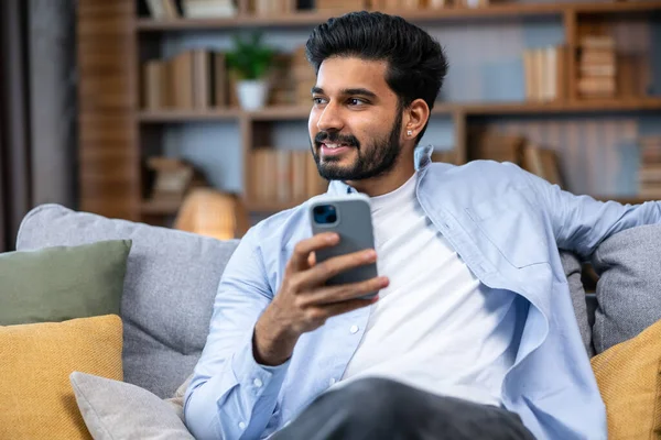 Çekici Gülümseyen Genç Adam Evdeki Koltukta Dinleniyor Cep Telefonu Kullanıyor — Stok fotoğraf