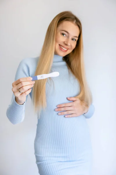 妊娠検査結果を保持する美しい女性は 完璧な笑顔でポジティブで幸せな立場と笑顔を見ています — ストック写真