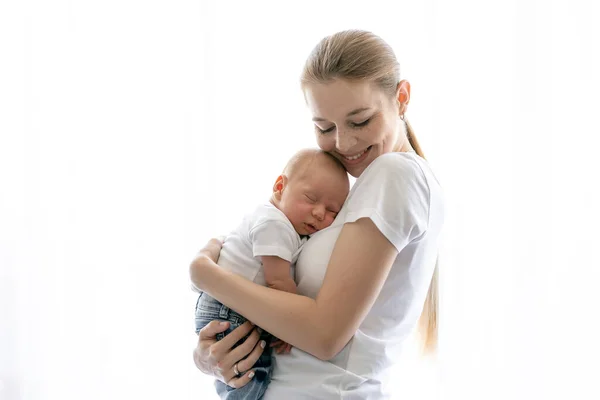 Όμορφη Μητέρα Κρατώντας Χαριτωμένο Μωρό Στα Χέρια Στέκεται Από Λευκό — Φωτογραφία Αρχείου