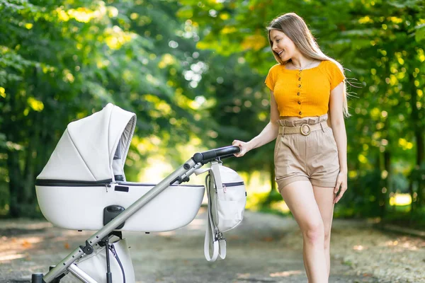 Smiling Blonde Lady Pulls Little Kid Rolling Grey Baby Carriage — Stock Photo, Image