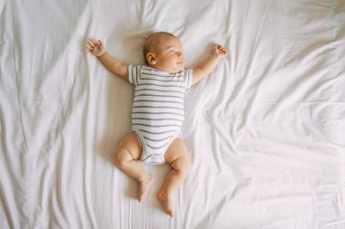Üst görünüm uyuyan yeni doğmuş bebek, yatağın kollarında ve bacaklarında uzanıyor. Temiz, taze ve rahat çarşaflar.