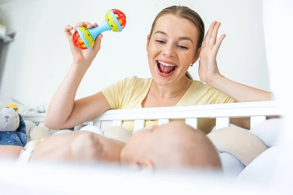 Νεαρή Μητέρα Κουνώντας Πλαστικό Πολύχρωμο Παιχνίδι Κουδουνίστρα Ενώ Παίζει Μωρό — Φωτογραφία Αρχείου