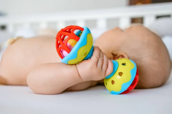 Baby Lying Home Bed Holding Rattle Toy — Stock Photo, Image