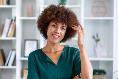 Neşeli Afro-Amerikan kadın kameraya bakıyor ve gülümsüyor.