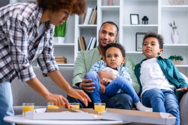 Keyifli çocuklar ve babalar ev yapımı ev yapımı pizza yemek için beklerken anneleri onu parçalara ayırıyor.