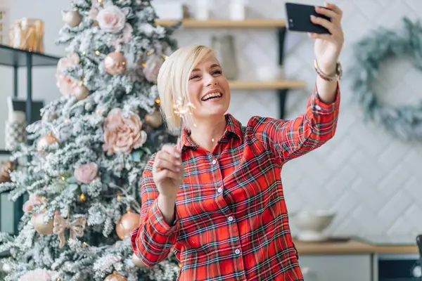 クリスマスツリーの背景に輝く陽気な女性 セルフィーを取るか ビデオリンクで挨拶 — ストック写真