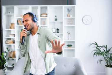 Kaygısız Şarkıcı. Neşeli genç adam en sevdiği şarkıyı söylüyor uzaktan kumandayı mikrofon olarak kullanıyor, kablosuz kulaklık takarak dans ediyor. Heyecanlı adam evde eğleniyor.