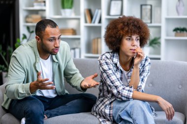 Kanepede oturan yorgun ve stresli kadının portresi. Agresif koca evde karısına bağırıyor. Aile skandalı, kriz, aile içi şiddet, istismar kavramı.