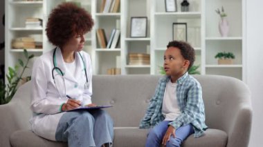 Genç afro-amerikan doktor çocuk doktoruyla konuşan küçük bir çocuk not panosuna not alıyor ve sağlık hizmetlerini sağlık kontrolündeki genç siyahi öğrencilere anlatıyor. 