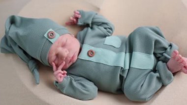 Yeşil elbiseli şirin yeni doğmuş bebek yatakta yatıyor.