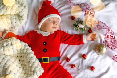 Noel Baba şapkalı, kırmızı elbiseli şirin bir bebek evde uyuyor..