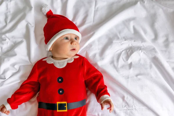 圣诞节早上 身穿圣诞老人服装的婴儿躺在床上 — 图库照片