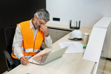 Baş ağrısı, dizüstü bilgisayar ve mimar adam stresi, ağrı ve zihinsel sağlık sorunu proje yönetimi, planlama ve bütçe stratejisi düşünme. Ofis masasına otur.