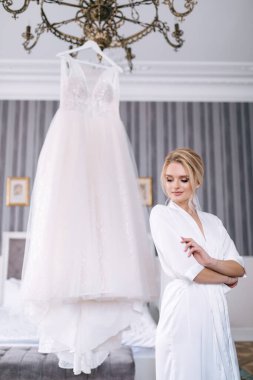 Gelinin sabah hazırlıkları. İçerideki askıda asılı gelinliğin yanında güzel bornozlu bir kız..