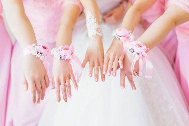 Gelin ve nedimelerin yakın çekim elleri. Nedimelerin ellerinde gül ve pembe kurdele.