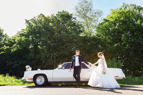 レトロカーの近くの花嫁と一緒に歩くグルーム ストック写真