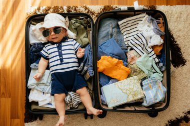 Sevimli bebek ve yerde yatan bavulun içinde tatil için eşyalar. Bebekle deniz tatili, konsept